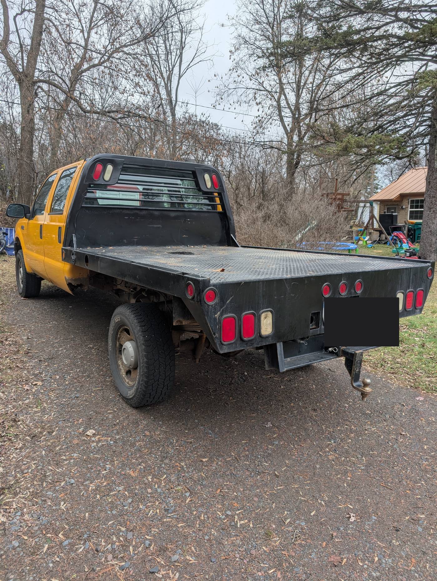 Yellow Ford Super Duty crew cab with black diamond-plate flatbed after finish work